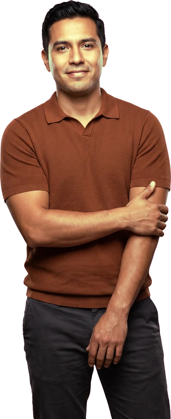 Smiling man standing with his arms crossed, wearing a brown knit polo shirt